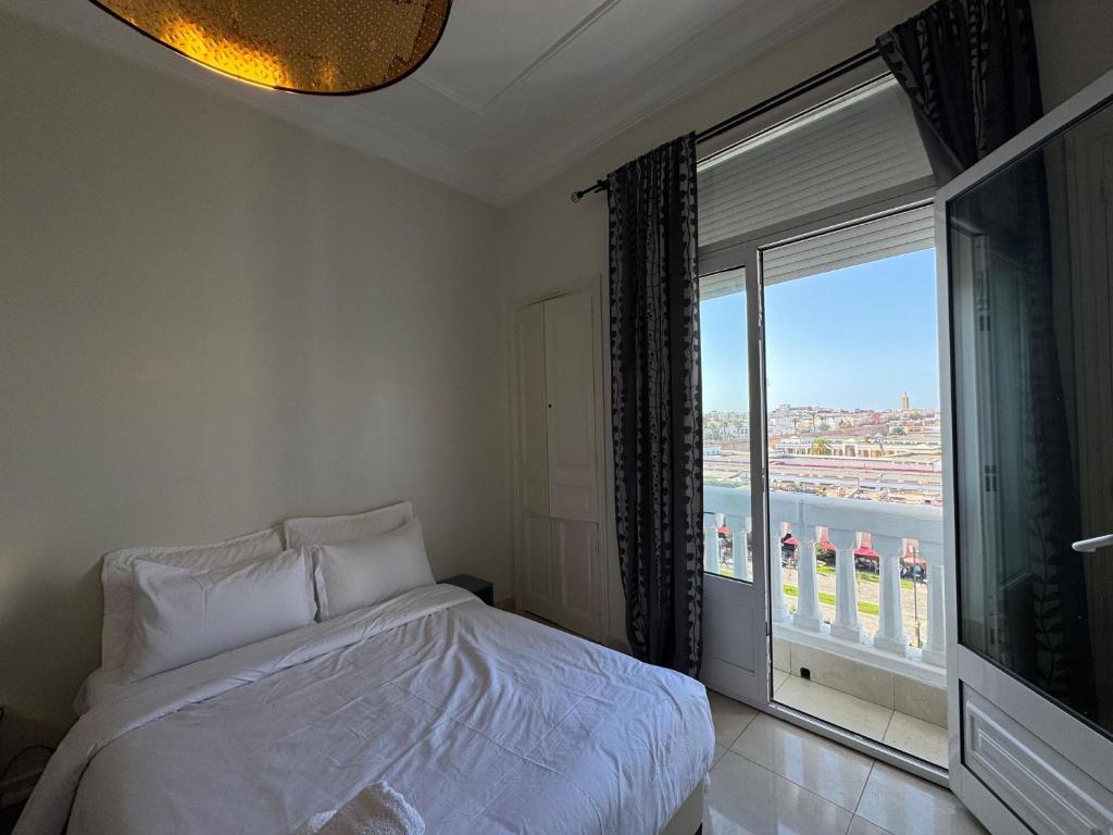 ein Schlafzimmer mit einem Bett und einem großen Fenster in der Unterkunft Apartement Bab lhad in Rabat