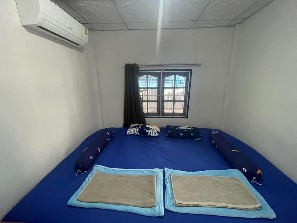 een blauw bed in een kamer met een raam bij โฮมสเตย์ติดแม่น้ำปิง in Sam Ngao