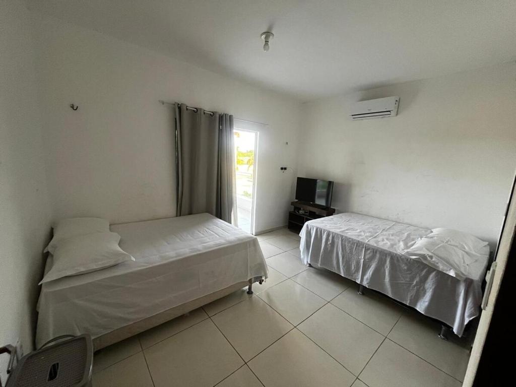 a bedroom with two beds and a television in it at Casa Simões in Fortim