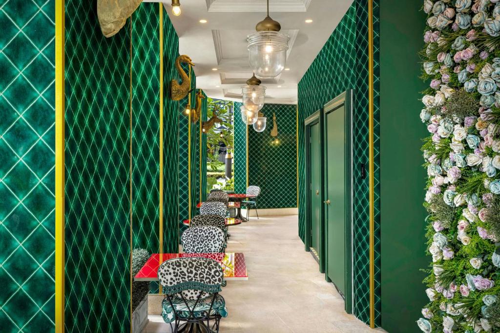 a restaurant with green walls and a row of tables and chairs at The Serangoon House Little India, Singapore, a Tribute Portfolio Hotel in Singapore