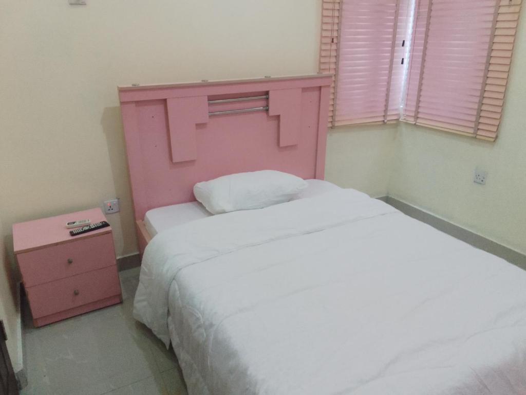 1 dormitorio con cabecero rosa y cama blanca en Frills Apartments, en Aja
