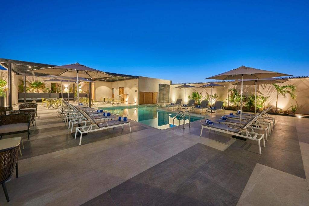 - Piscina con sillas y sombrillas por la noche en City Express Plus by Marriott Mazatlan, en Mazatlán