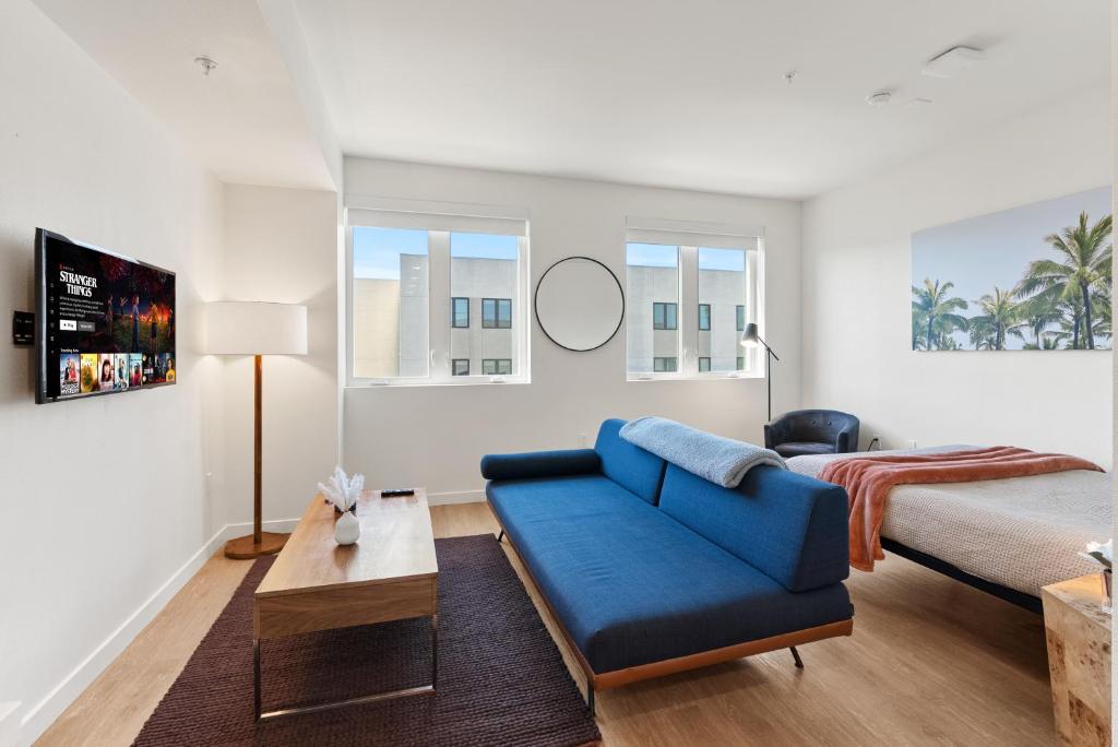 a living room with a blue couch and a bed at Bright Studio on Sunset Blvd Pool, Parking, Gym in Los Angeles
