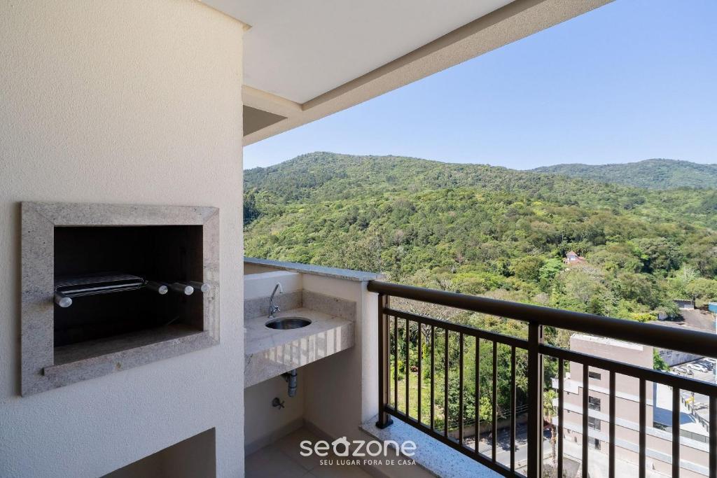 een balkon met een wastafel en bergen op de achtergrond bij Studio c/ churrasq. a 750m da UFSC - PST1409 in Florianópolis