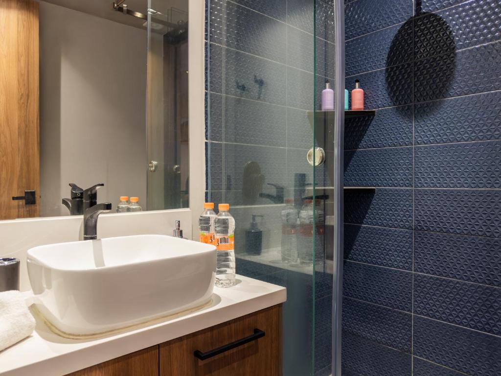 A modern bathroom vanity beside a dark-tiled glass shower.