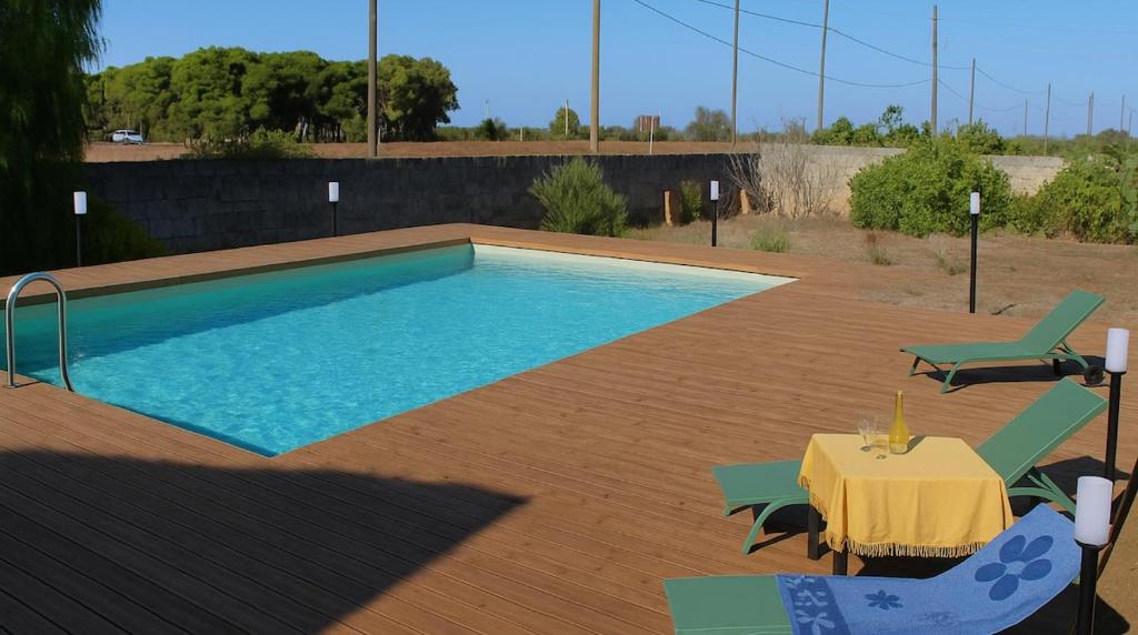 una piscina con un tavolo e due sedie e un tavolo e un piano del tavolo di Porto Selvaggio Villa a Santa Caterina di Nardò