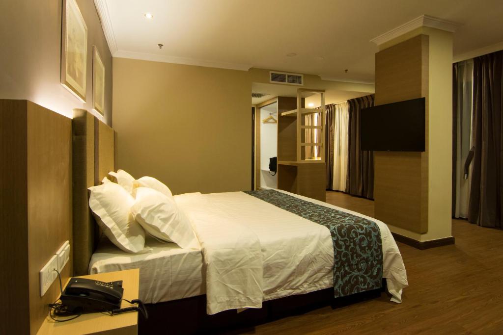 a hotel room with a bed and a television at Hotel Anika Kluang in Kluang