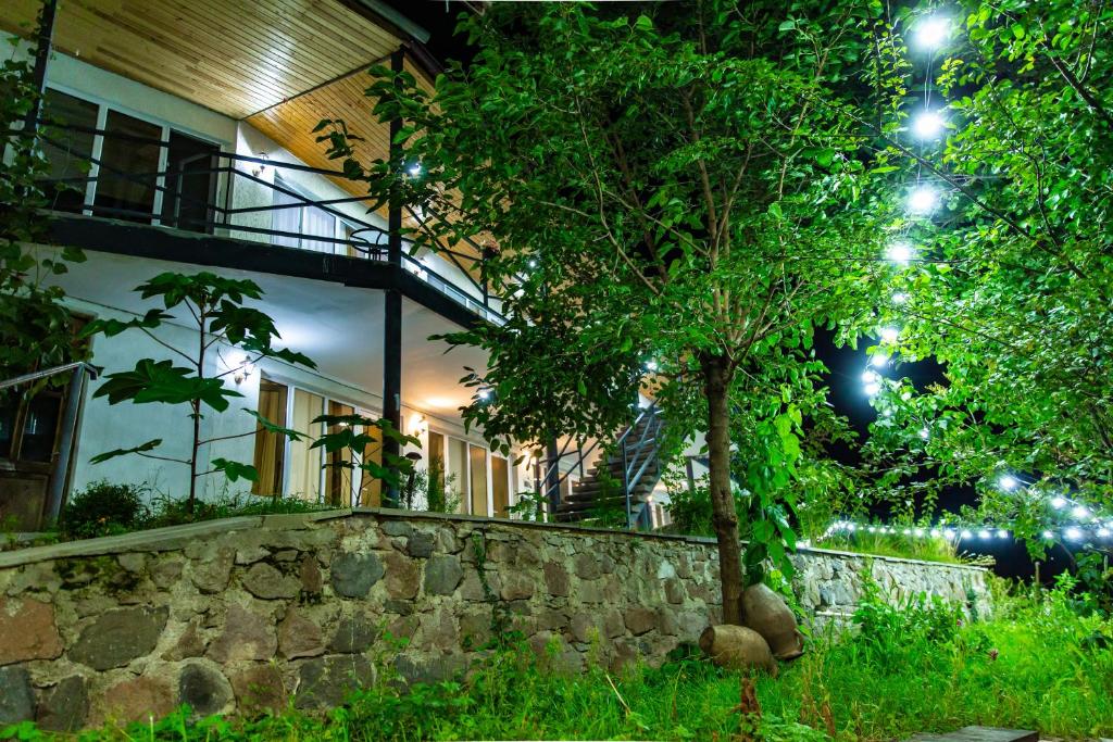 a house with a tree in front of a stone wall at Hotel-GVALA in Vardzia