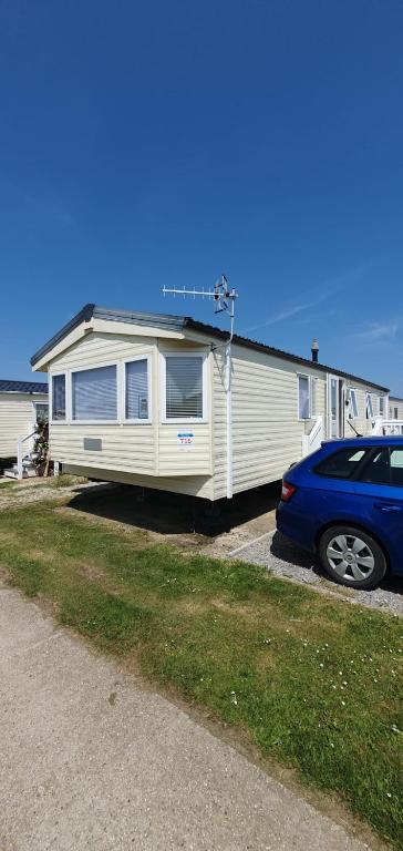 a mobile home with a car parked in front of it at Hayling Island Caravan in Hayling Island