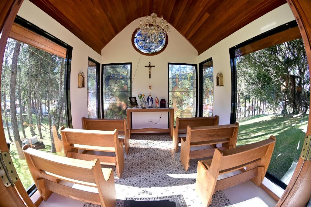 a chapel with wooden chairs and a cross on the wall at Pequena Suíça Hotel Boutique in Chácara