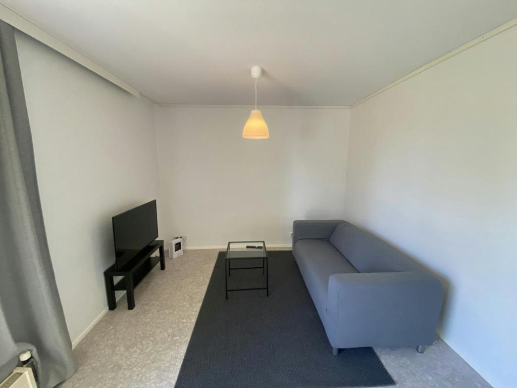a living room with a blue couch and a tv at Practical Apartment for 2 in Smedsbacka
