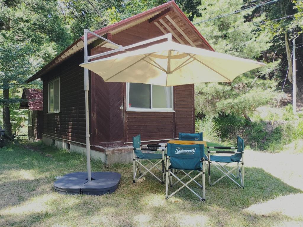 a table and chairs under an umbrella in front of a cabin at Nodaira Campsite - Vacation STAY 43841v in Ichiba