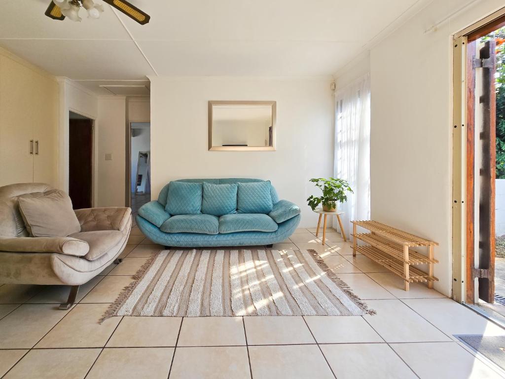 un soggiorno con un divano blu e una sedia di Coastal Retreat a East London