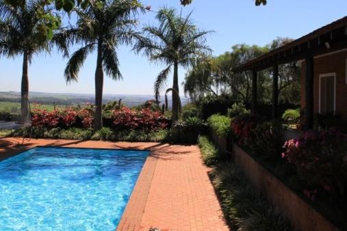 une piscine devant une maison avec des palmiers dans l'établissement Chácara Vila Toscana, 