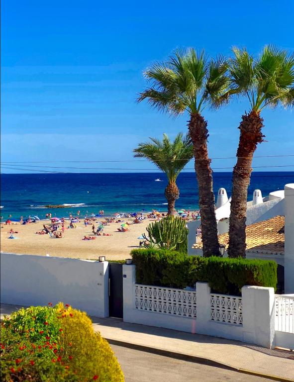 a beach with palm trees and people on the beach at "Ancla-Blanca" Ocean View Duplex 2min Beach Cabo Roig - La Zenia in Orihuela Costa