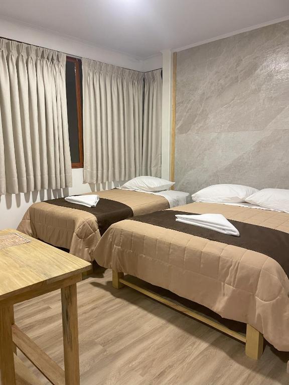 a hotel room with two beds and a table at Hotel 888 in Oxapampa