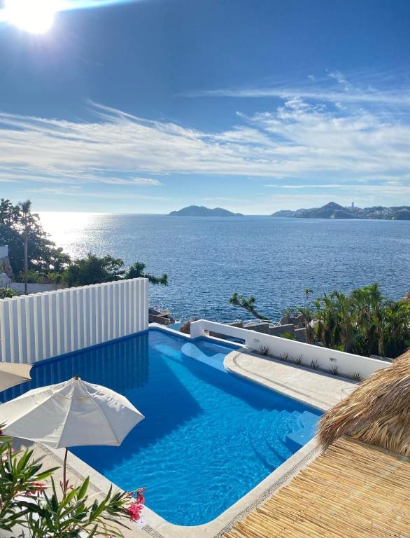 a swimming pool with a view of the ocean at Villa MAJUM Acapulco in Acapulco