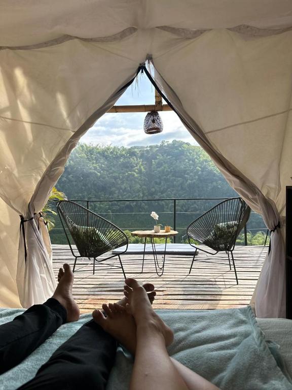 una persona acostada en una cama con los pies dentro de una tienda de campaña en Encanto Toscano, en Quimbaya
