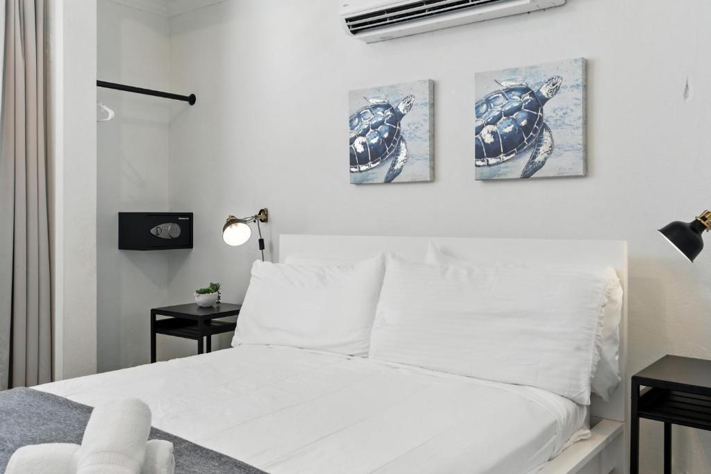 a bedroom with a white bed with three pictures on the wall at Pr Rentals Walk To La Placita & Condado Beach in San Juan