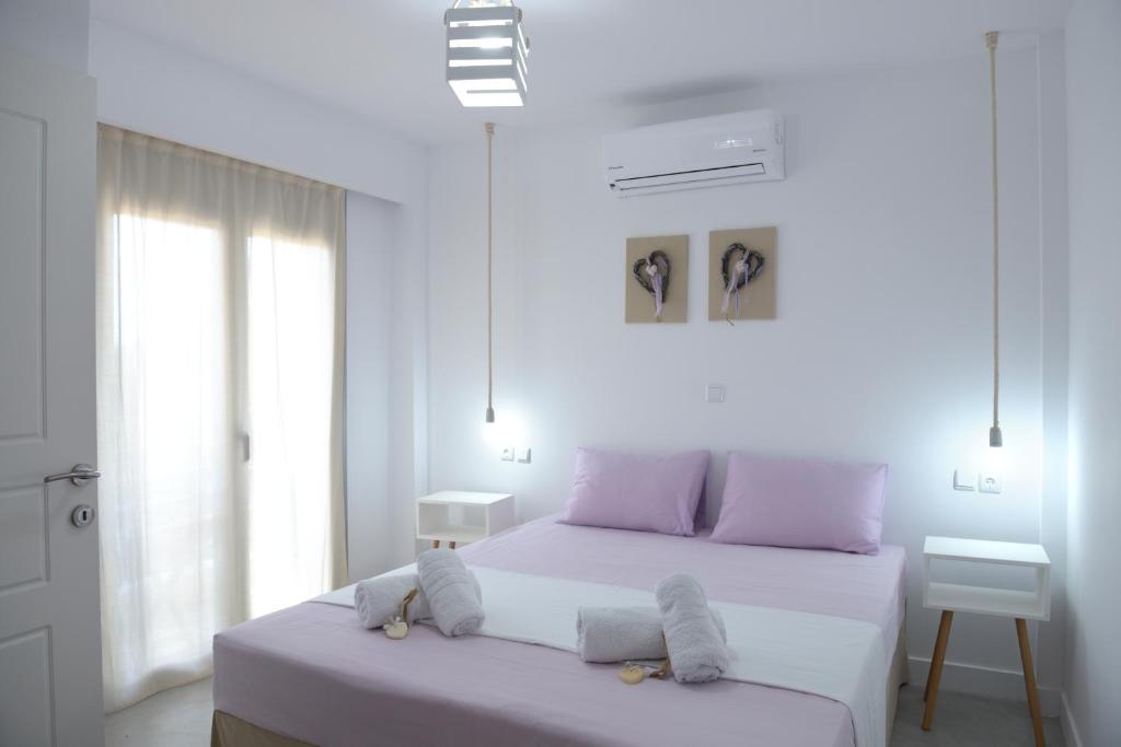 a white bedroom with two beds and a window at Axos Apartments in Hersonissos