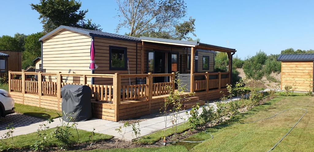レネッセにあるNieuw chalet JV10 Renesse met 3 slaapkamers 2 badkamers airco veranda en parkeren bij accommodatieの庭にデッキ付きの木造キャビン