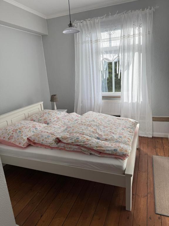1 cama en un dormitorio con ventana y colcha en Landhof est 1886, en Niederdorla