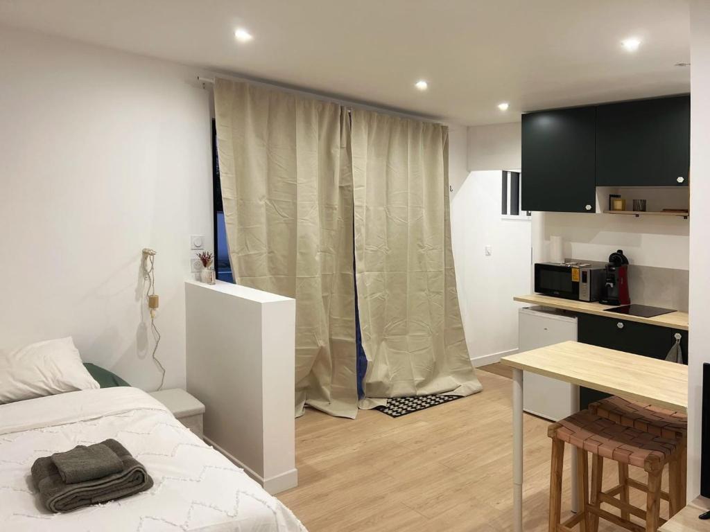 a bedroom with a bed and a desk and a kitchen at Charmant T1 bis in Mérignac