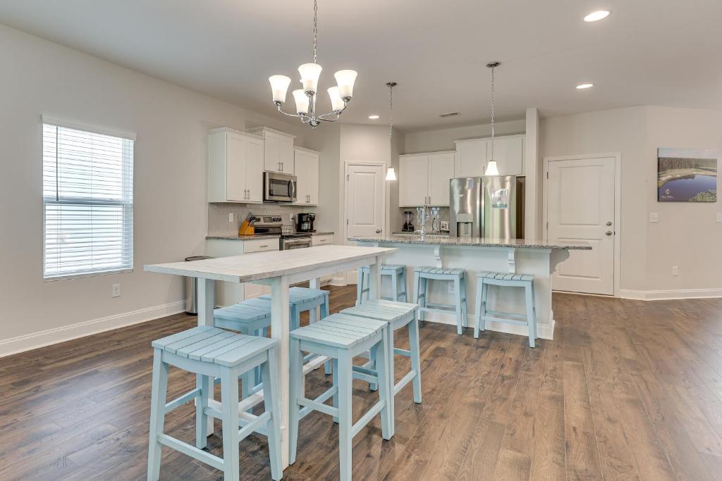 a kitchen with a table and some blue stools at 3 Mi to Sand! Ocean Isle Beach Escape Near Golf in Seaside
