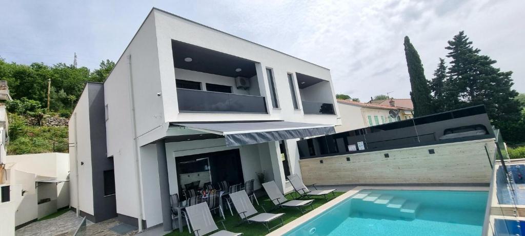 a large white house with a swimming pool and chairs at Villa Eva in Dramalj