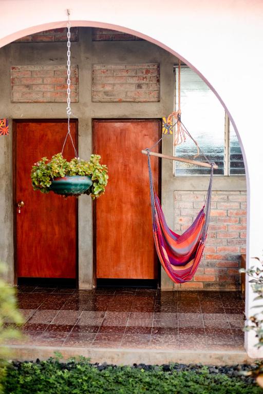 Una hamaca colgada frente a una casa con dos puertas. en Hostal Casa del Sol, en Suchitoto