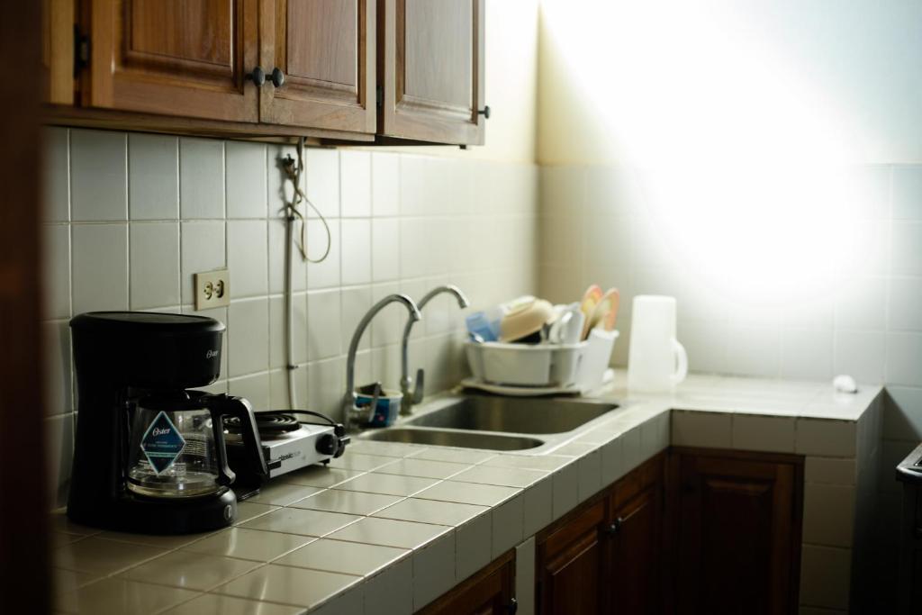 a kitchen counter with a sink and a coffee maker at Hostal Casa del Sol in Suchitoto
