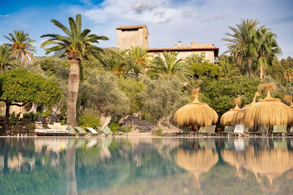 een resort met palmbomen en een zwembad bij Hotel Es Port in Port de Soller