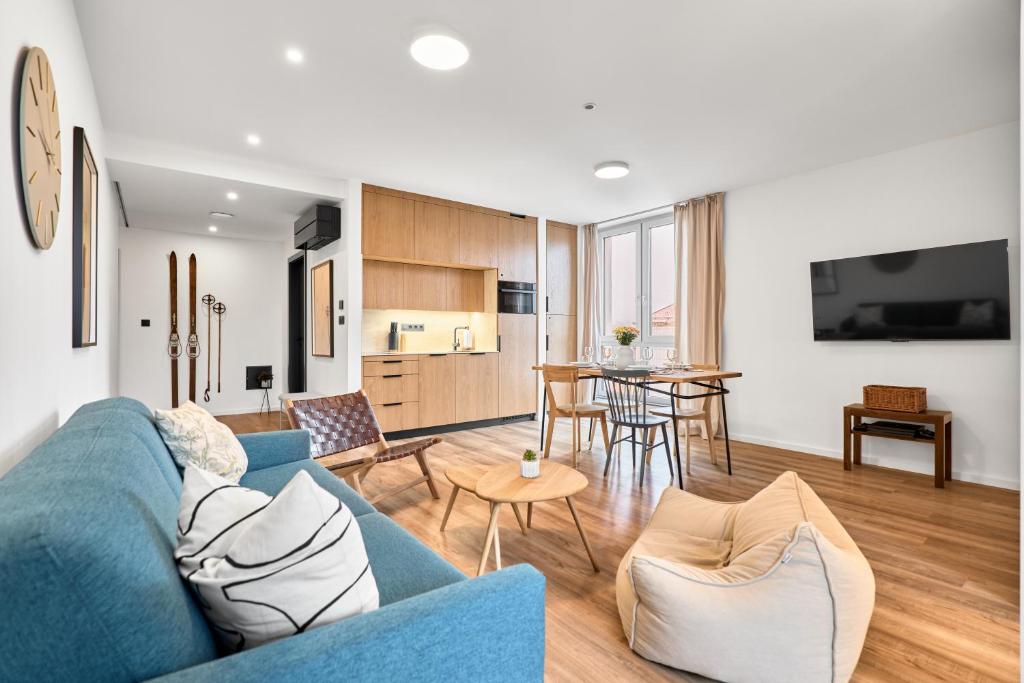 Una sala de estar con un sofá azul y una cocina. en Heřmánek by Mountain ways, en Abertamy