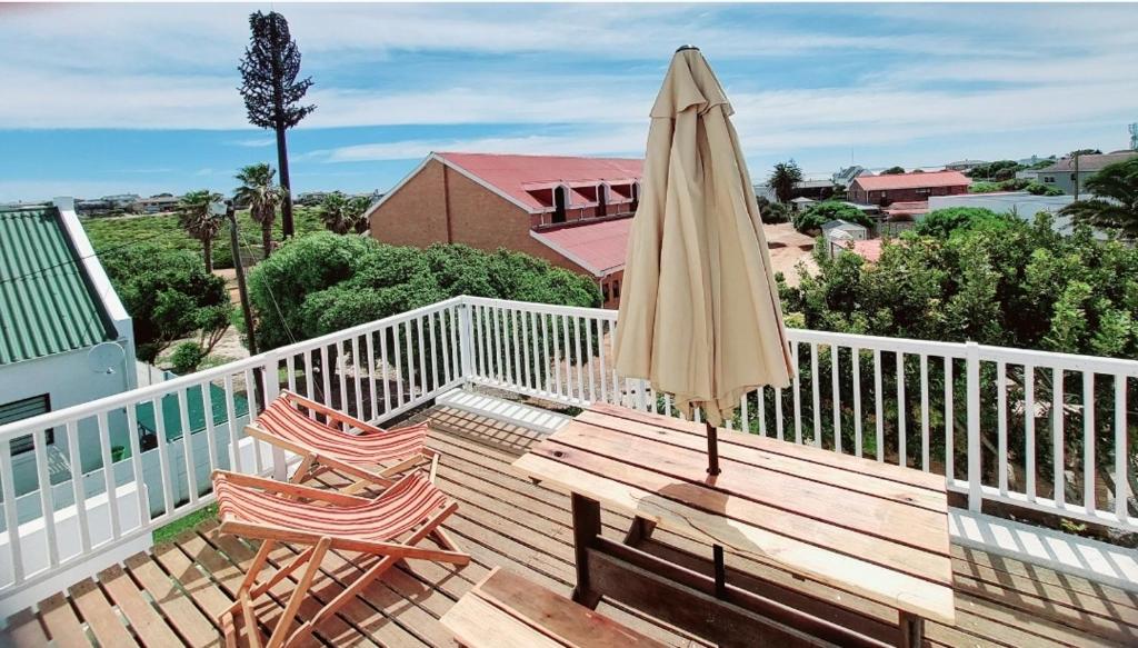 a patio umbrella and two chairs on a deck at 8 Eden Villa in Yzerfontein