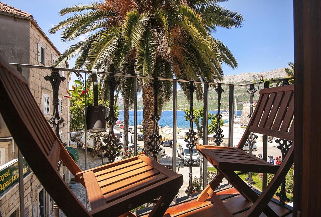 a balcony with two chairs and a palm tree at San Teodoro in Korčula