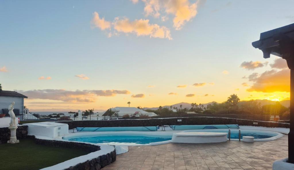 une piscine avec un coucher de soleil en arrière-plan dans l'établissement Detached Villa with Stunning Mountain and Sea Views, 14m Pool & sunken Hot Tub, à Puerto del Carmen