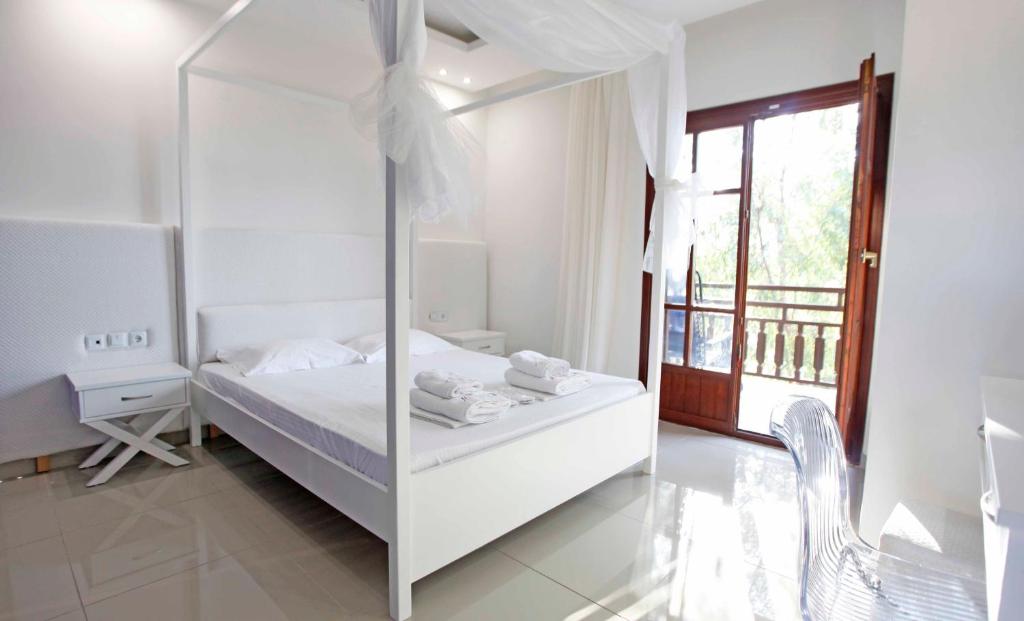 a white bedroom with a bed and a window at Macedon in Limenas