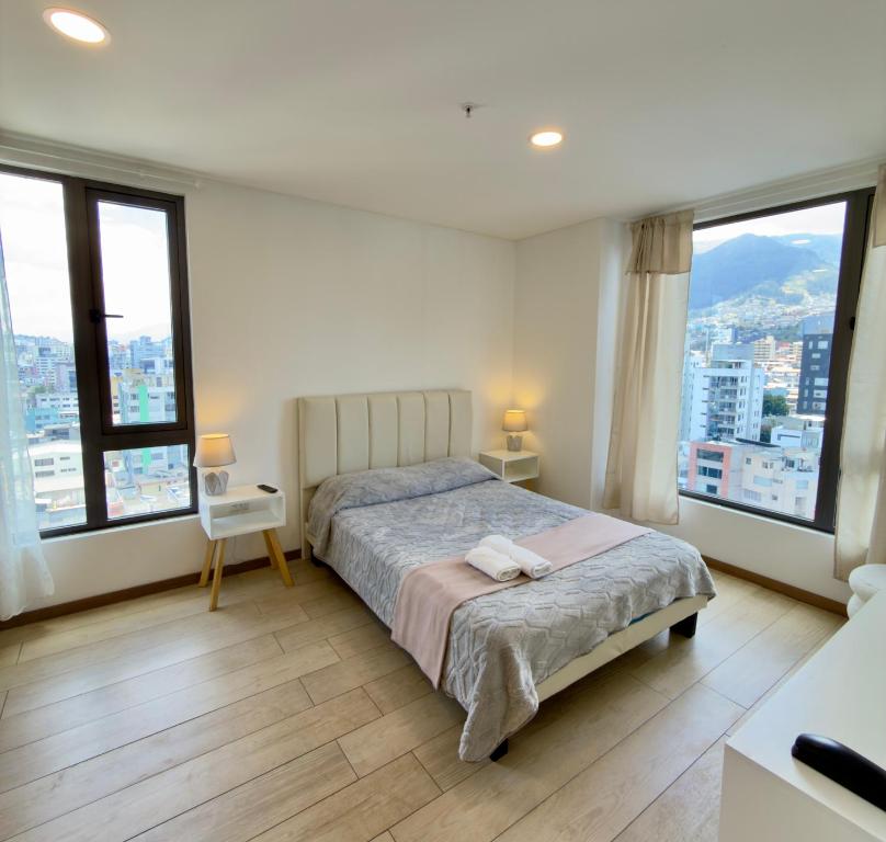 キトにあるLuxury Mini Suite, La Carolinaのベッドと大きな窓のある寝室