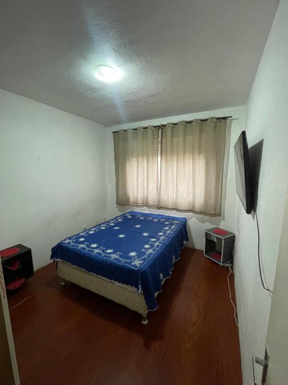 Schlafzimmer mit einem Bett mit blauem Laken in der Unterkunft Apartamento inteiro in Porto Alegre