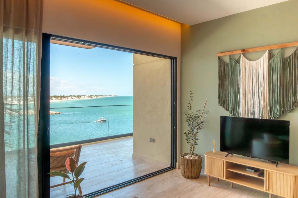 a living room with a large sliding glass door with a view of the ocean at Yucalpeten Resort Marina - Dpto de 2 Recámaras en Progreso - Lujo Frente a la Playa & Amenidades Top in Progreso