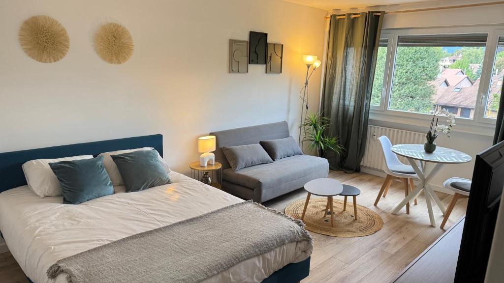 a bedroom with a bed and a couch and a table at Studio cosy aux portes de Geneve in Ferney-Voltaire