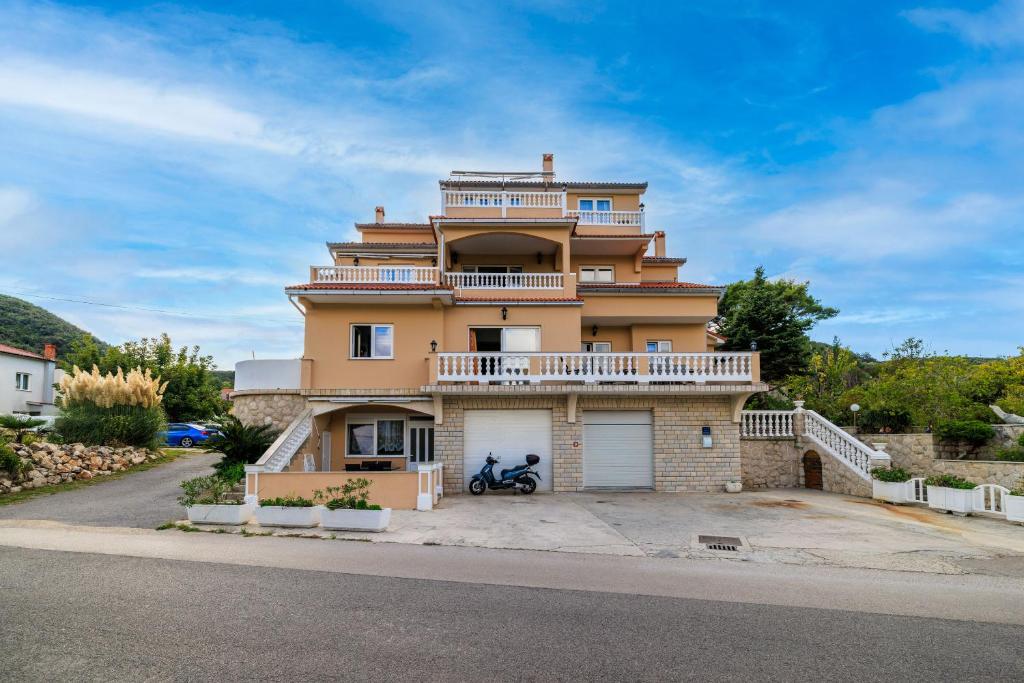 a large yellow building with a balcony on a street at Apartments Mig in Supetarska Draga