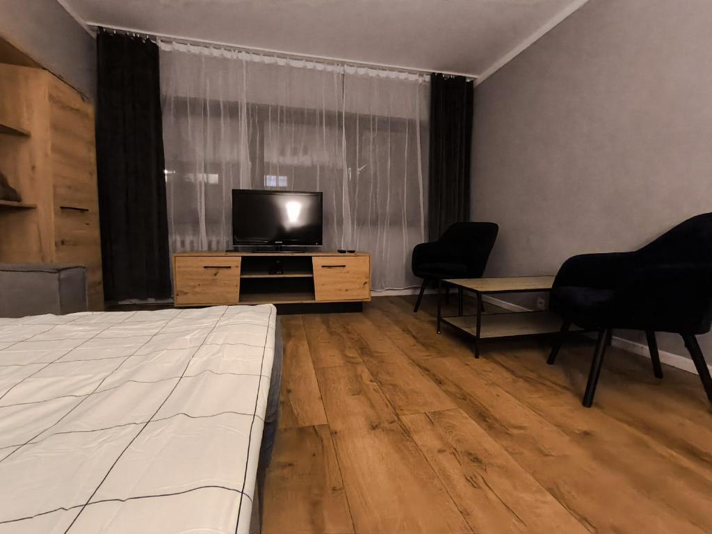 a room with a bed and a television and chairs at Mieszkanie 41 in Częstochowa