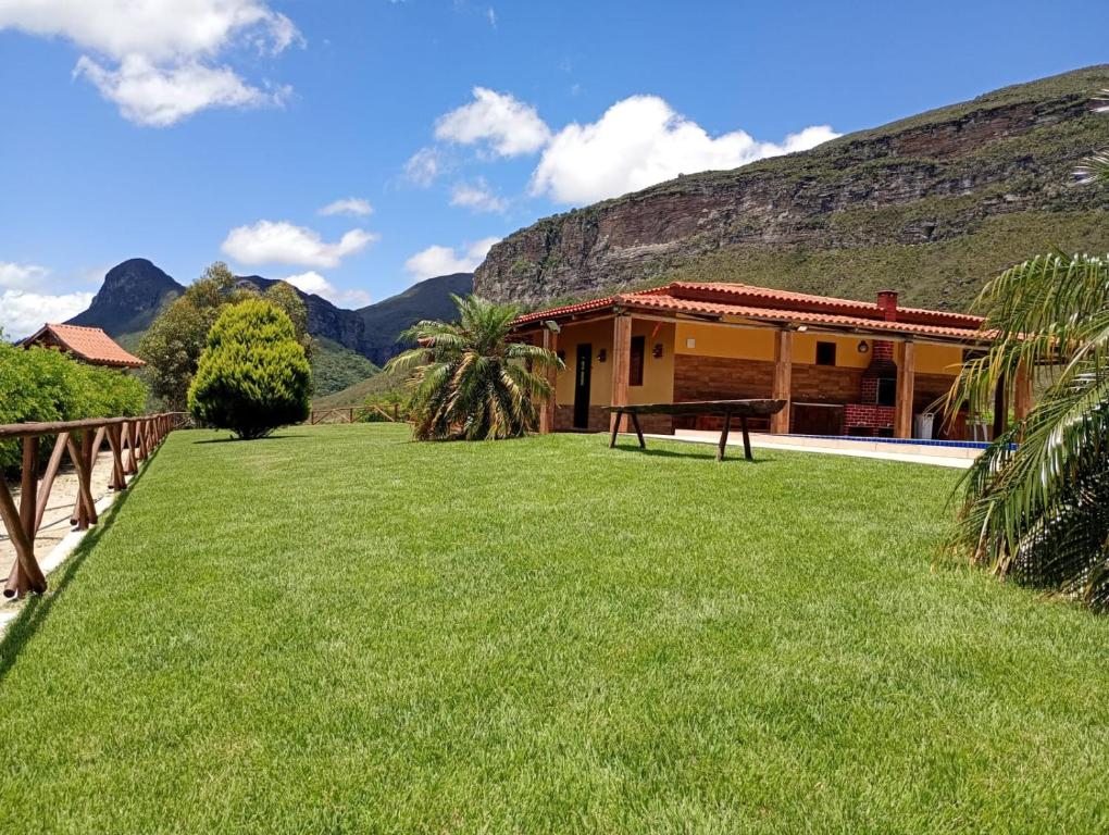 a house with a green lawn in front of a building at Casa de Campo Ibicoara in Ibicoara