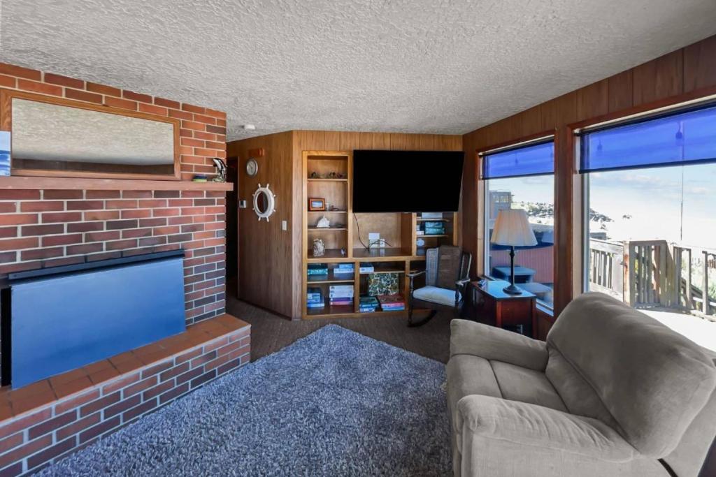 sala de estar con chimenea de ladrillo y TV en Ocean's Edge Escape, en Twin Rocks