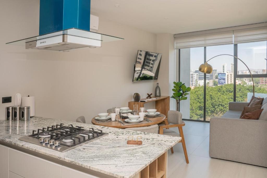 a kitchen with a stove top oven next to a living room at Modern Stay in the Heart of Guadalajara in Guadalajara