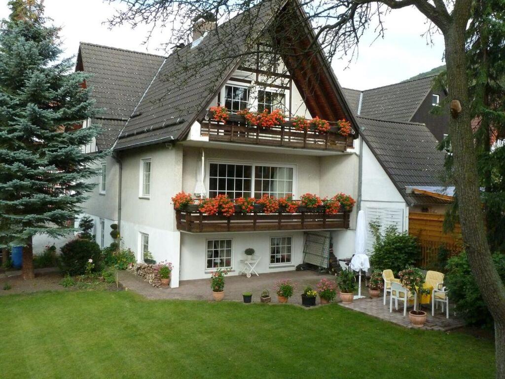 a white house with a balcony with flowers on it at Haus Roswita in Bad Harzburg