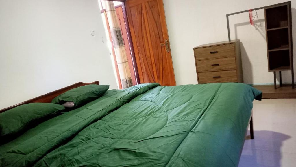 a bedroom with a bed with green sheets and a dresser at Taibessi in Dili