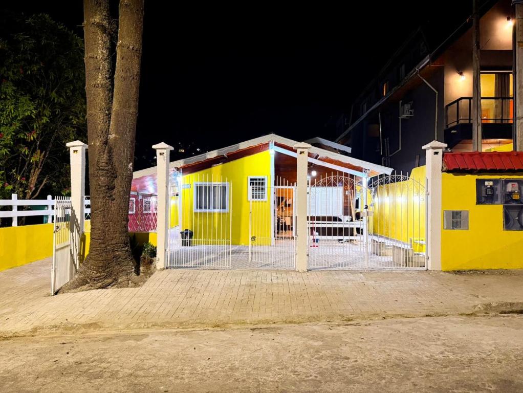 a yellow building with a fence and a tree at Memoriá in Campos do Jordão