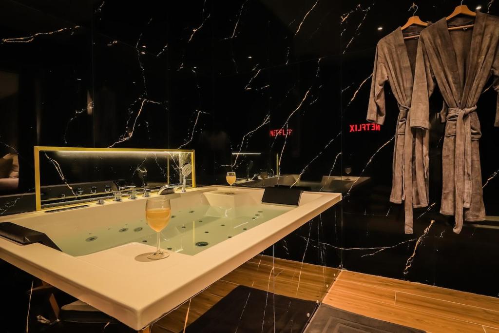 a bathroom with a tub with a glass of wine at Golden Suite - Elegance - Private Spa Jacuzzi in Lens